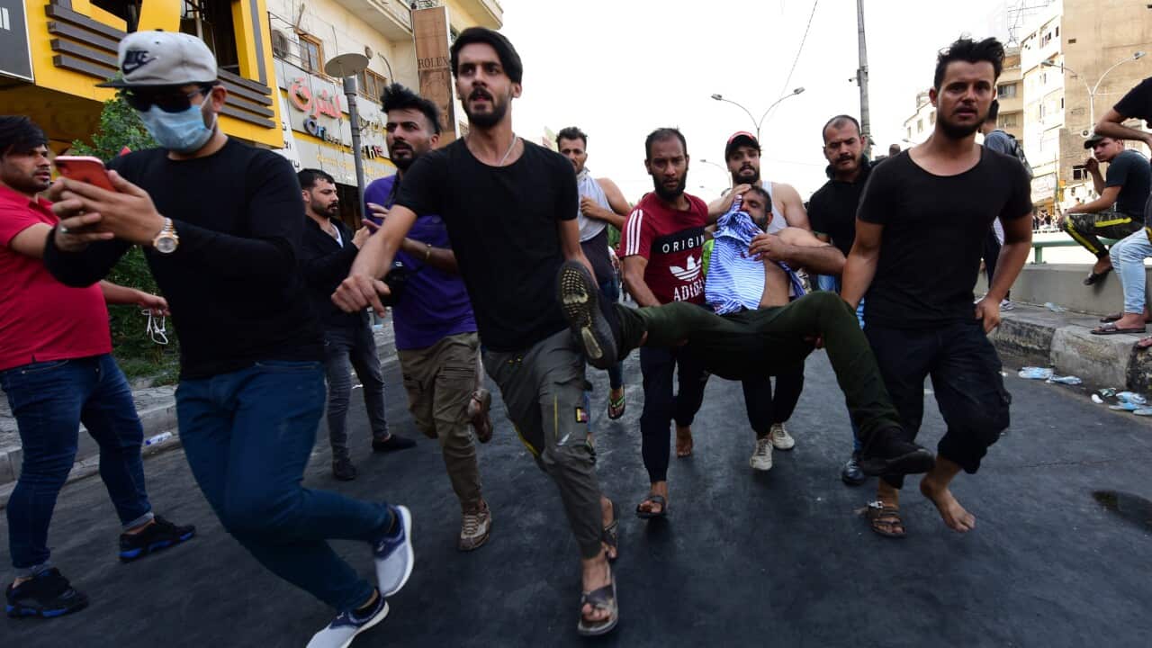 Iraqi protesters carry a wounded during clashes with Iraqi riot forces at a demonstration in al-Tahrir square, central Baghdad, Iraq.