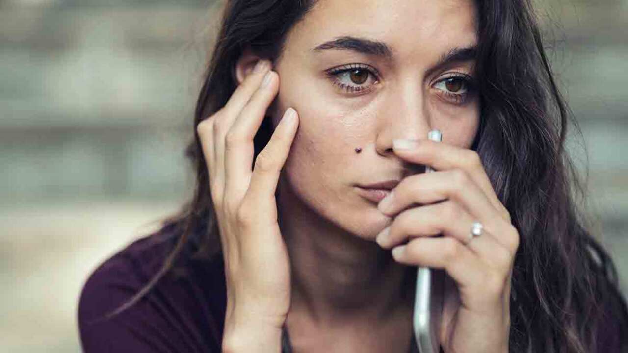 Distressed woman holding mobile phone