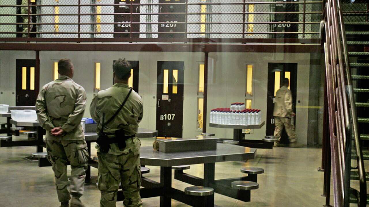 Guantanamo guards keep watch over a cell block with detainees
