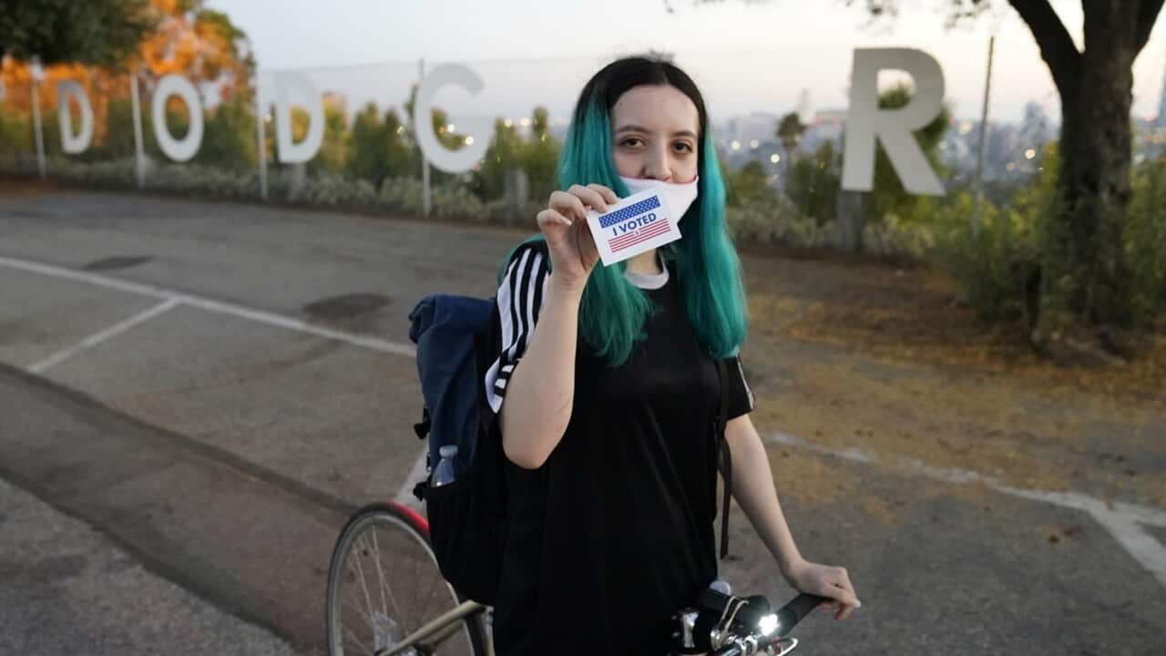 Young woman shows her "I VOTED" sticker after casting her ballot for the first time