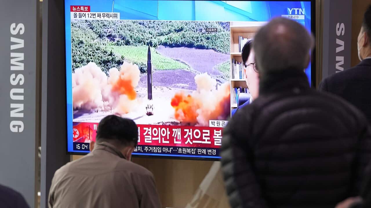 People watch a TV showing a file image of North Korea's missile launch during a news program.