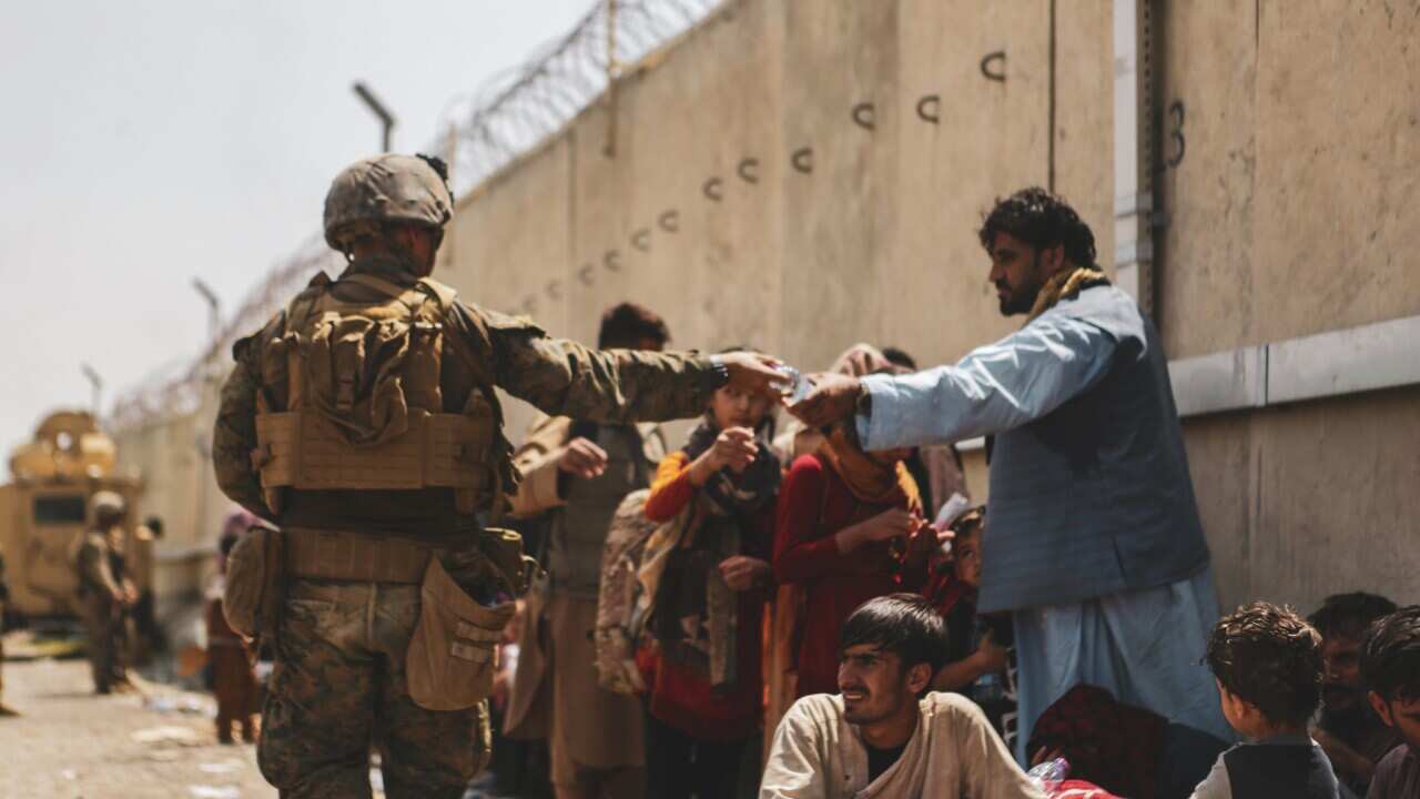 210822-M-TU241-1007 HAMID KARZAI INTERNATIONAL AIRPORT, Afghanistan (August 22, 2021 via Sipa USA) A Marine with the 24th Marine Expeditionary unit (MEU via Sipa USA) passes out water to evacuees during an evacuation at Hamid Karzai International Airport,