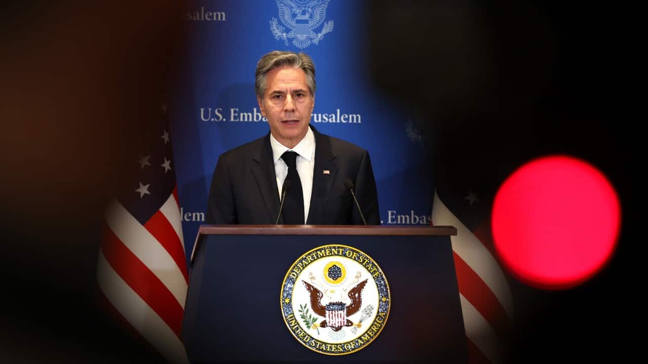US Secretary of State Antony Blinken speaks in front of a microphone while standing behind a lectern with the logo of the US Department of State.
