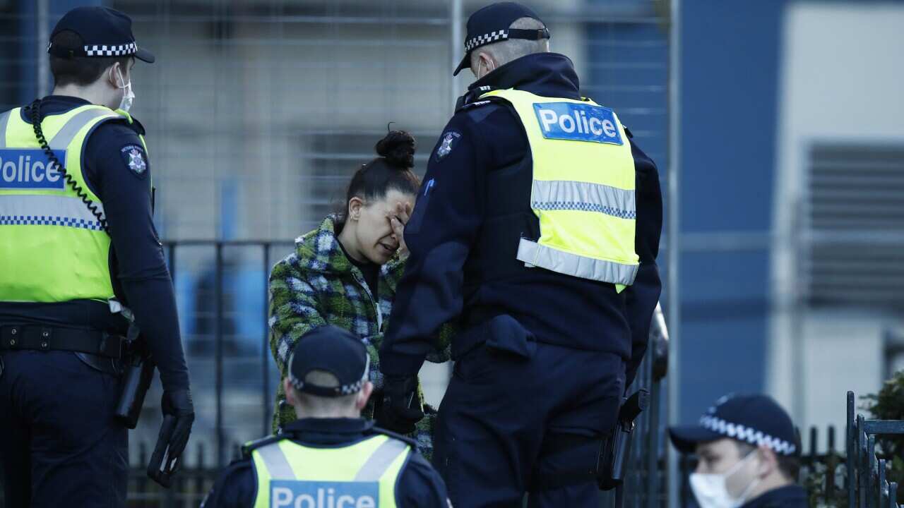 A woman speaks to police after attempting to leave public housing towers on Racecourse Road in Flemington, Melbourne, Sunday, July 5, 2020