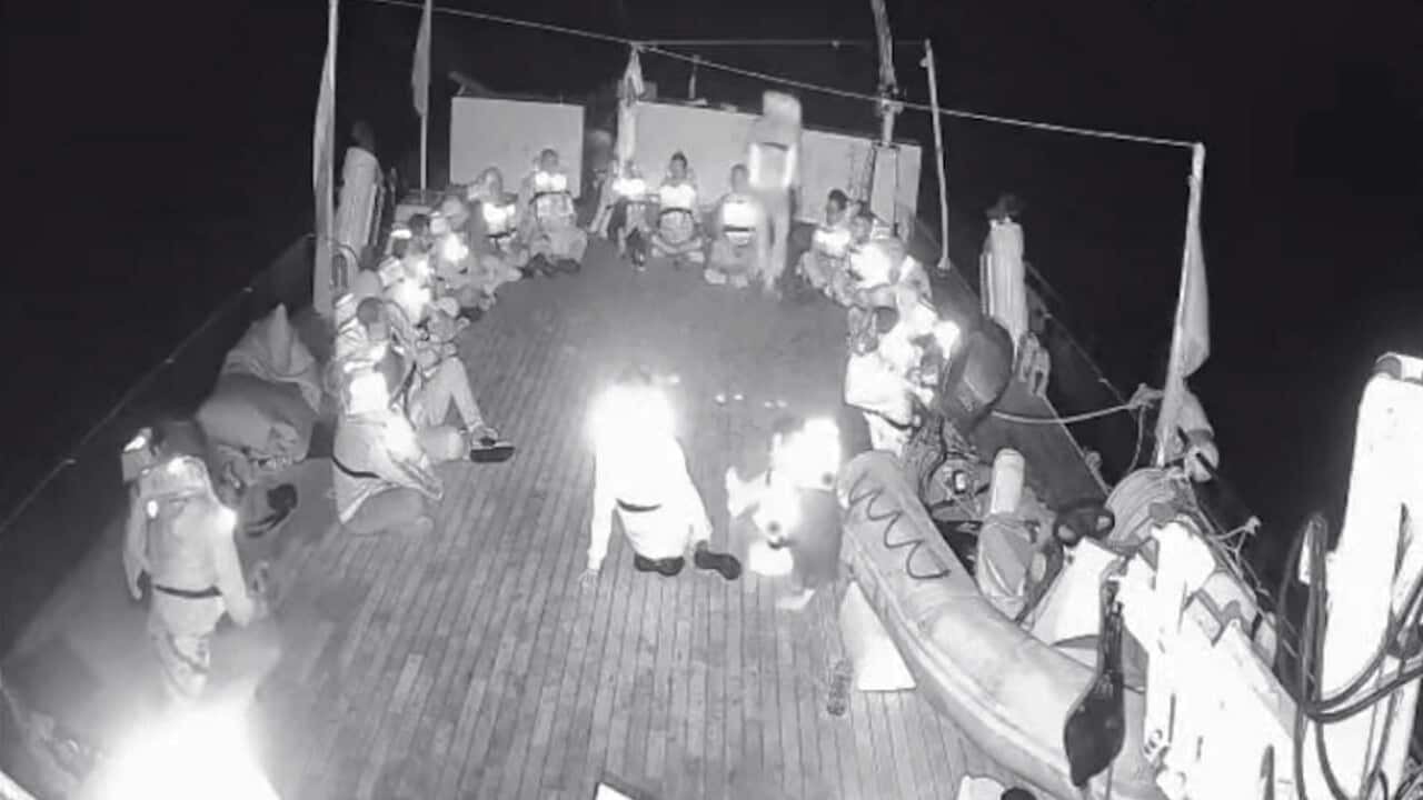 A black and white photo of people sitting on the deck of a vessel.