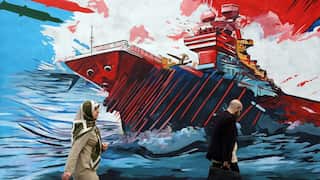 A man and a woman walk past a mural depicting a ship