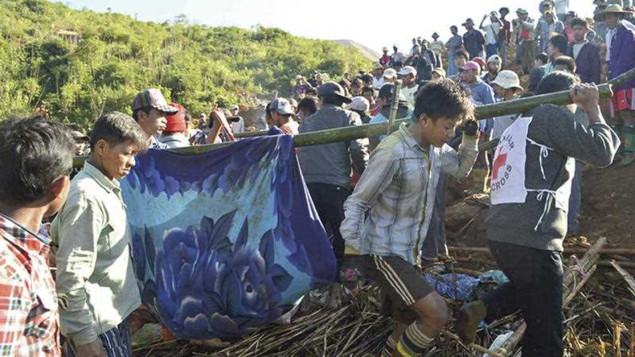 Myanmar Red Cross workers and people carry victims at a landslide affected area at Phakant jade mine, Kachin State, Myanmar.