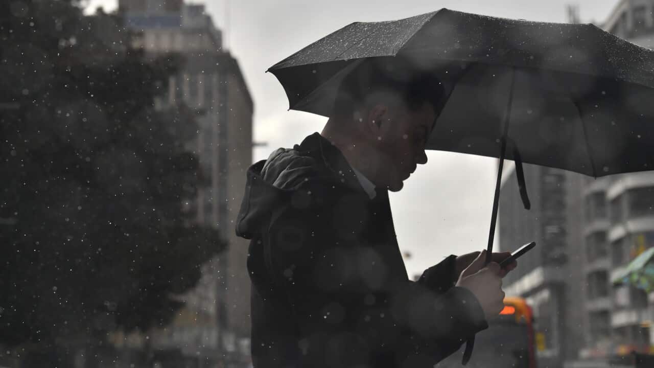 A man is seen walking under an umbrella on a rainy day.