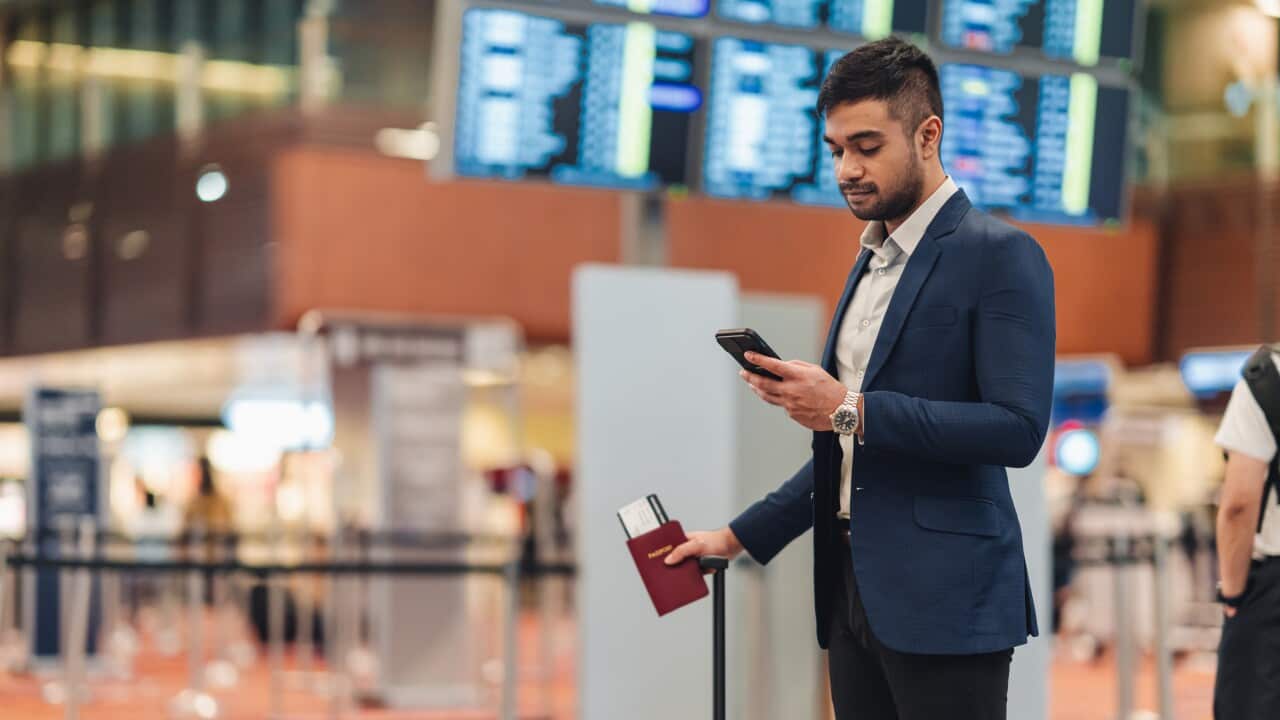 Young businessman waiting in the airport and texting with his phone