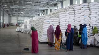 Workers clean the floor as sacks of food earmarked for the Tigray and Afar regions sits in piles in a warehouse of the World Food Programme (WFP) in Semera, the regional capital for the Afar region, in Ethiopia.