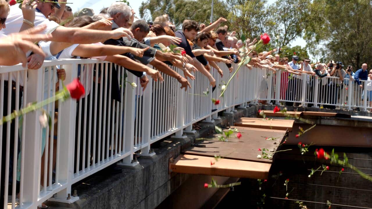Family and friends of survivors and those involved in the rescue efforts gather to throw 83 roses off the bridge in honour of those who died in the Granville train disaster 30 years ago in Sydney, Thursday, Jan.18, 2007.