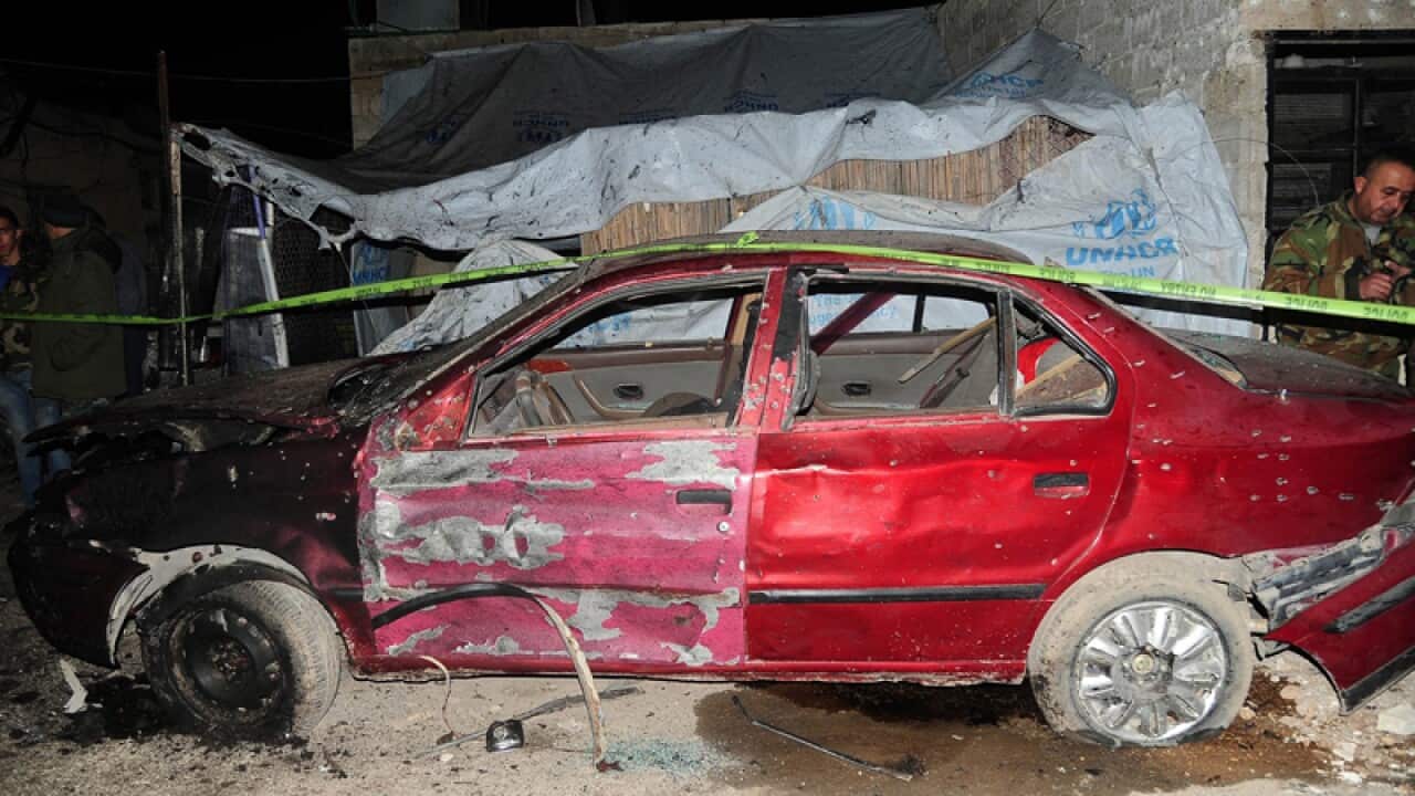 Syrian policemen inspect the site of a suicide attack