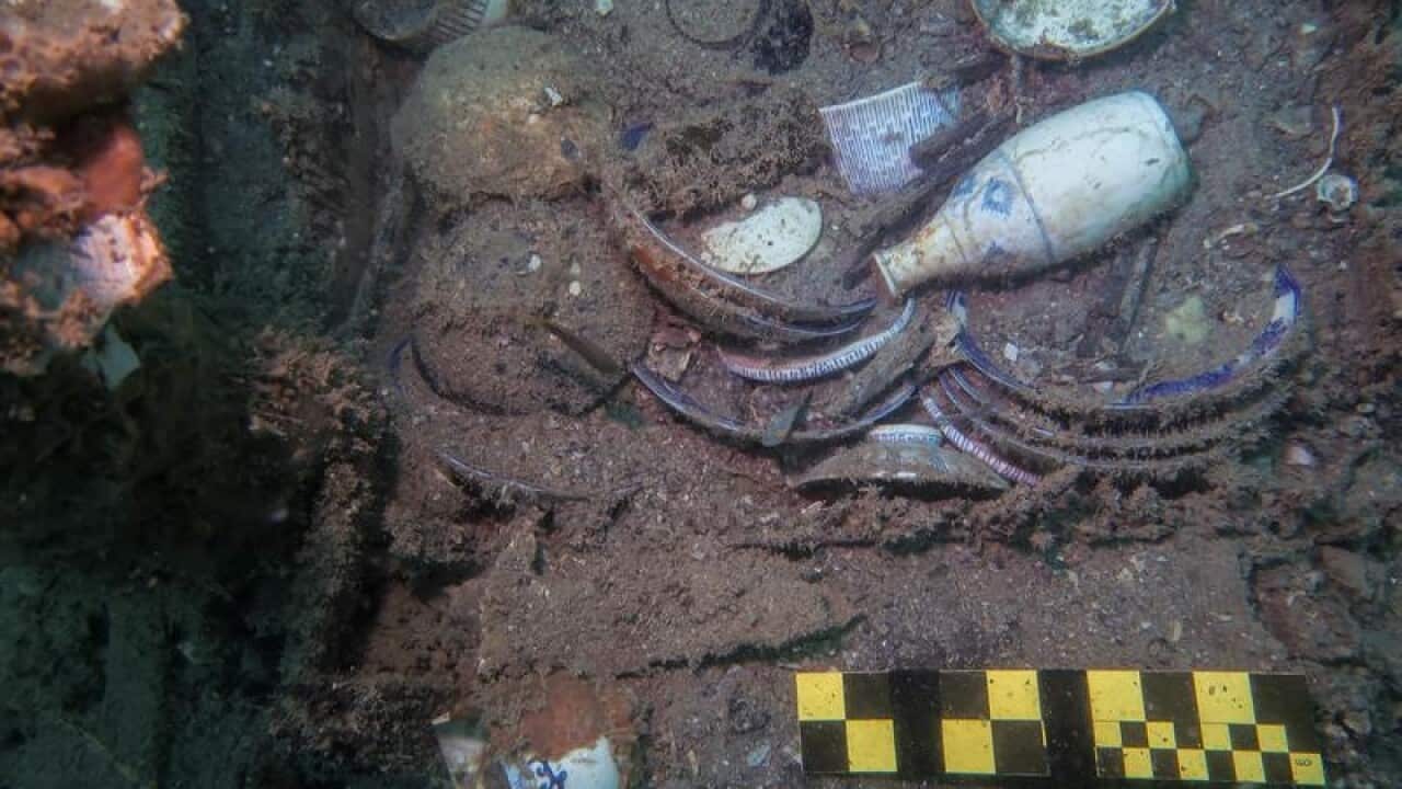 A shelf filled with dinnerware underwater in a shipwreck