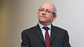 A man in a black suit, white shirt and red tie