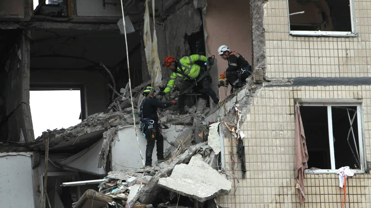 Rescue workers are seen working at a destroyed apartment block