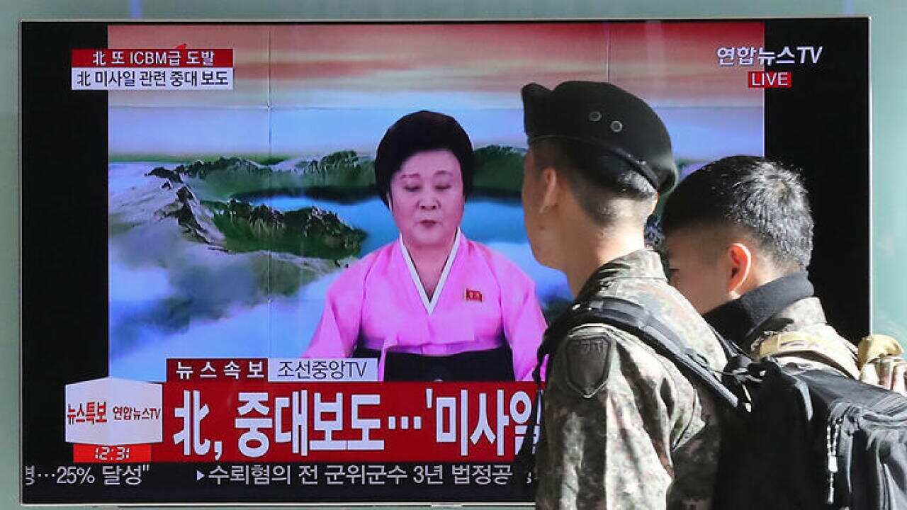 South Korean soldiers walk by a TV screen showing the live broadcast about North Korea's missile launch.