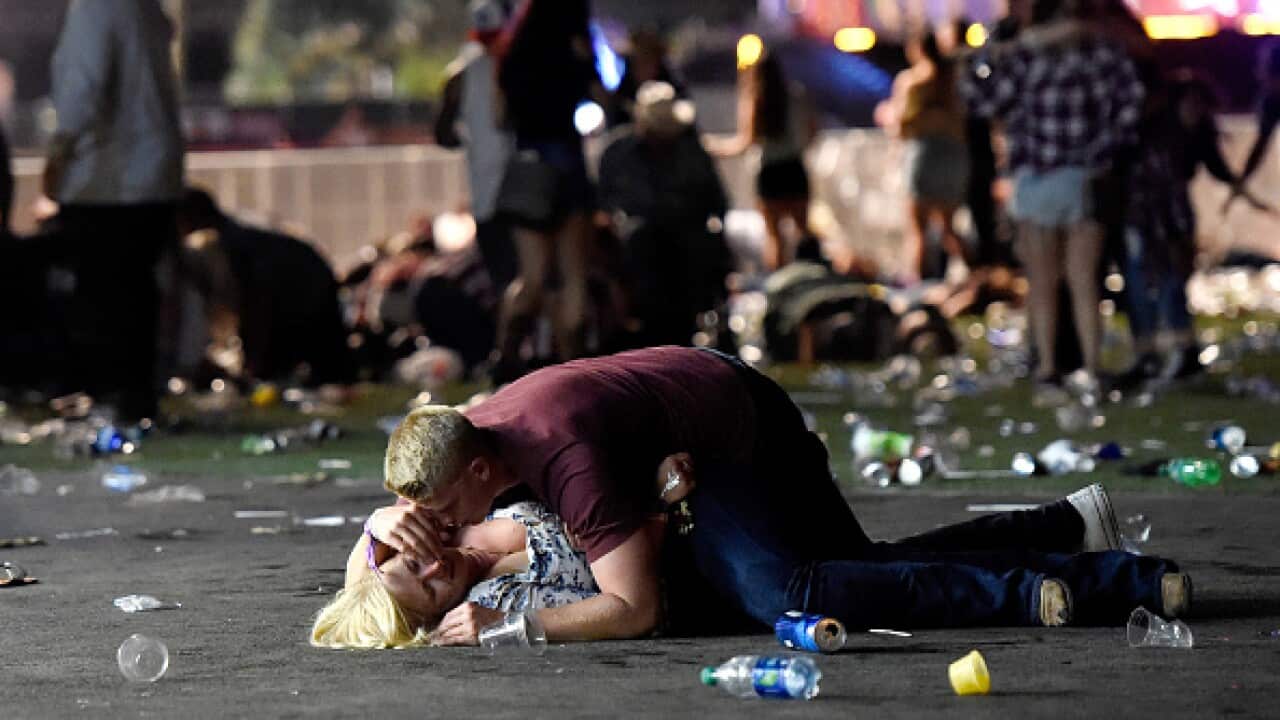 A man lays on top of a woman as others flee the Route 91 Harvest country music festival grounds after a active shooter was reported on October 1, 2017 in Las Vegas, Nevada. The photographer witnessed the man help the woman up and they walked away.