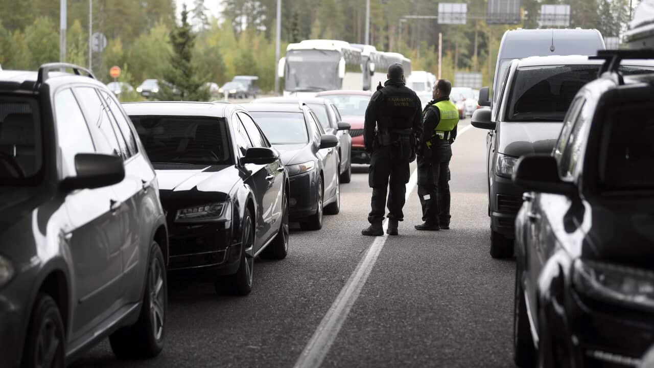 Finnish border guards stand amid queuing Russian vehicles at the Vaalimaa border check point