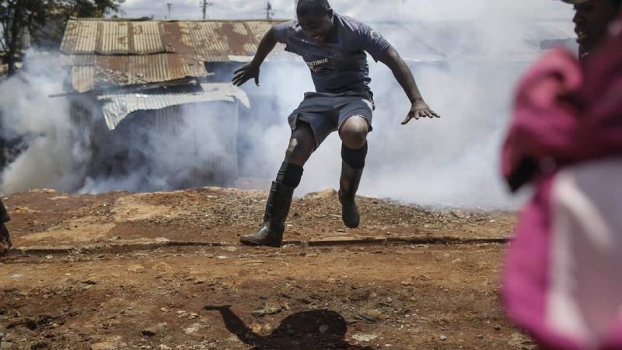A Kenyan protester jumps as tear gas is fired by police.