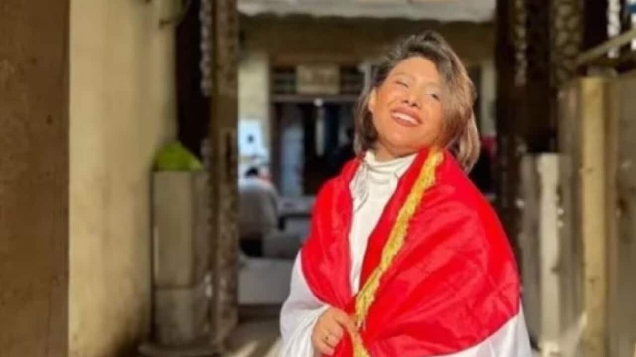 Tiba al-Ali wears a red shawl as she smiles.