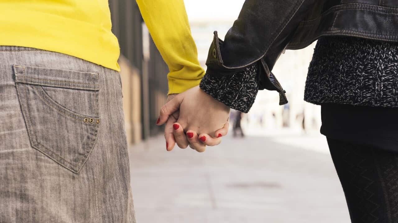 Two women holding hands on the street