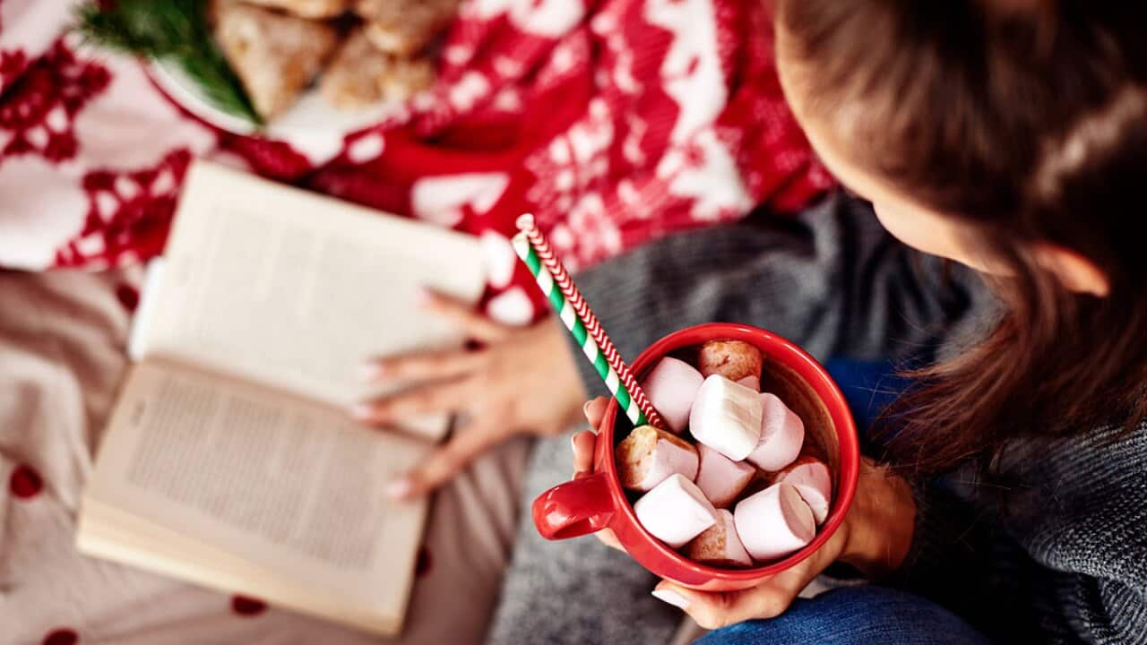 Reading book with hot chocolate in mug