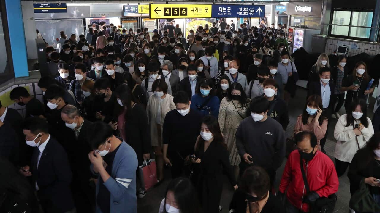 Commuters wearing masks change trains in the morning rush hour at a subway station in Seoul