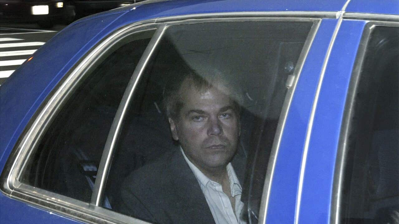 A man looks out of the window from the backseat of a car.