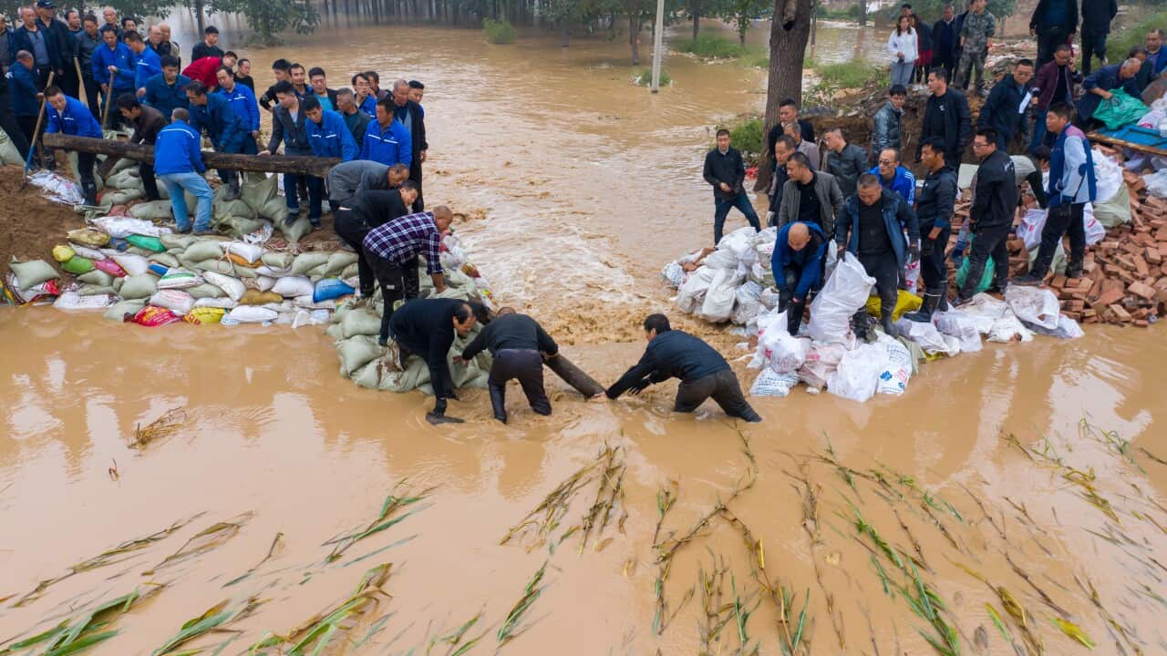 people in flood waters putting sandbacks down