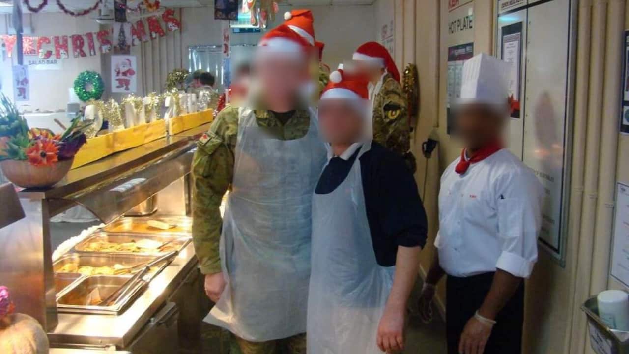 People posing for a photo inside. Some are wearing Santa hats