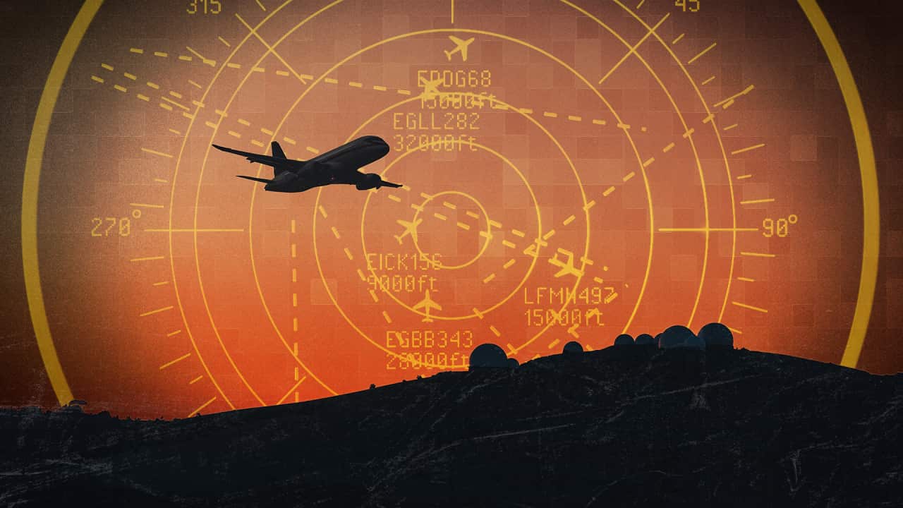 Silhouette of an airplane flying over dark terrain set against a orange radar display background.