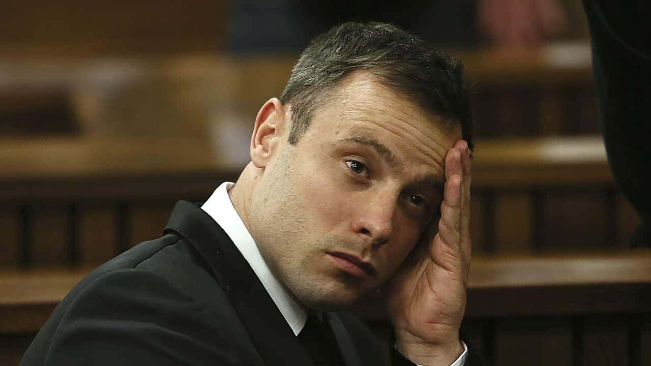 Oscar Pistorius leans his head on one hand.