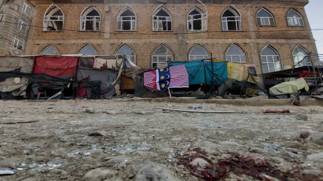 Broken glass on the ground and a building with damaged windows.