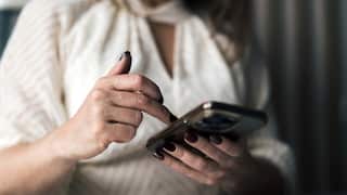 The hands of a woman holding a mobile phone.