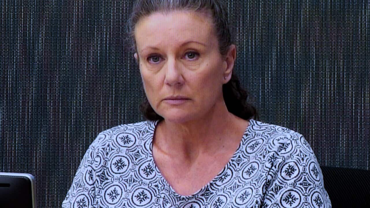 Kathleen Folbigg sits in front of microphone wearing a blue top.