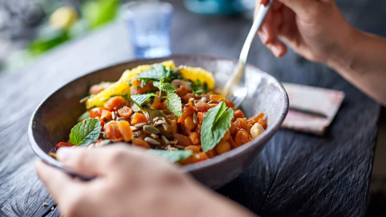 Healthy person eating organic chickpea salad from bowl with fork at rustic bohemian restaurant