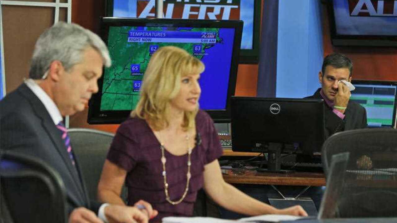 WDBJ-TV7 meteorologist Leo Hirsbrunner, right, wipes his eyes during the early morning newscast as anchors Kimberly McBroom, center, and guest anchor Steve Grant deliver the news at the station in Roanoke, Va., Thursday, Aug. 27, 2015.