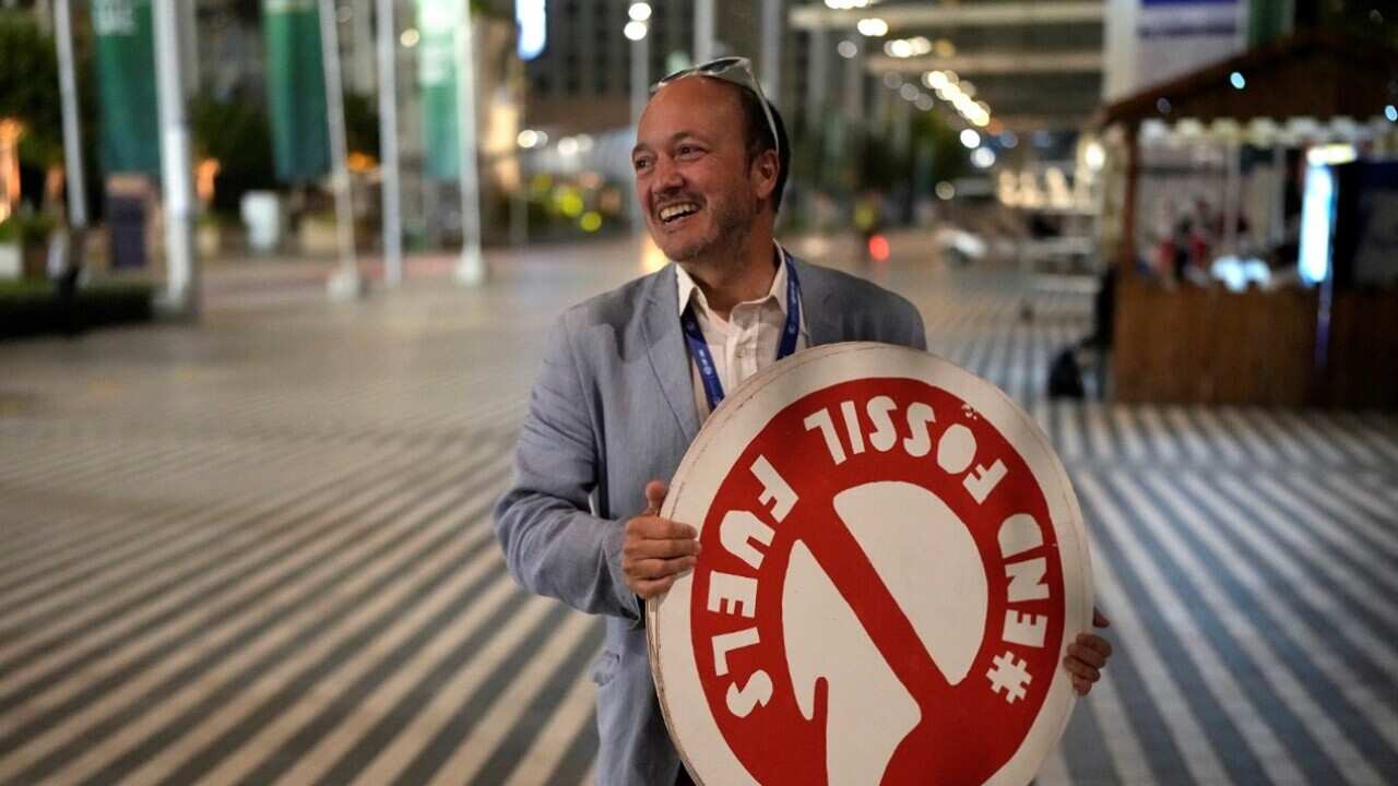 A man holds a sign that reads end fossil fuels at the COP 28.jpg
