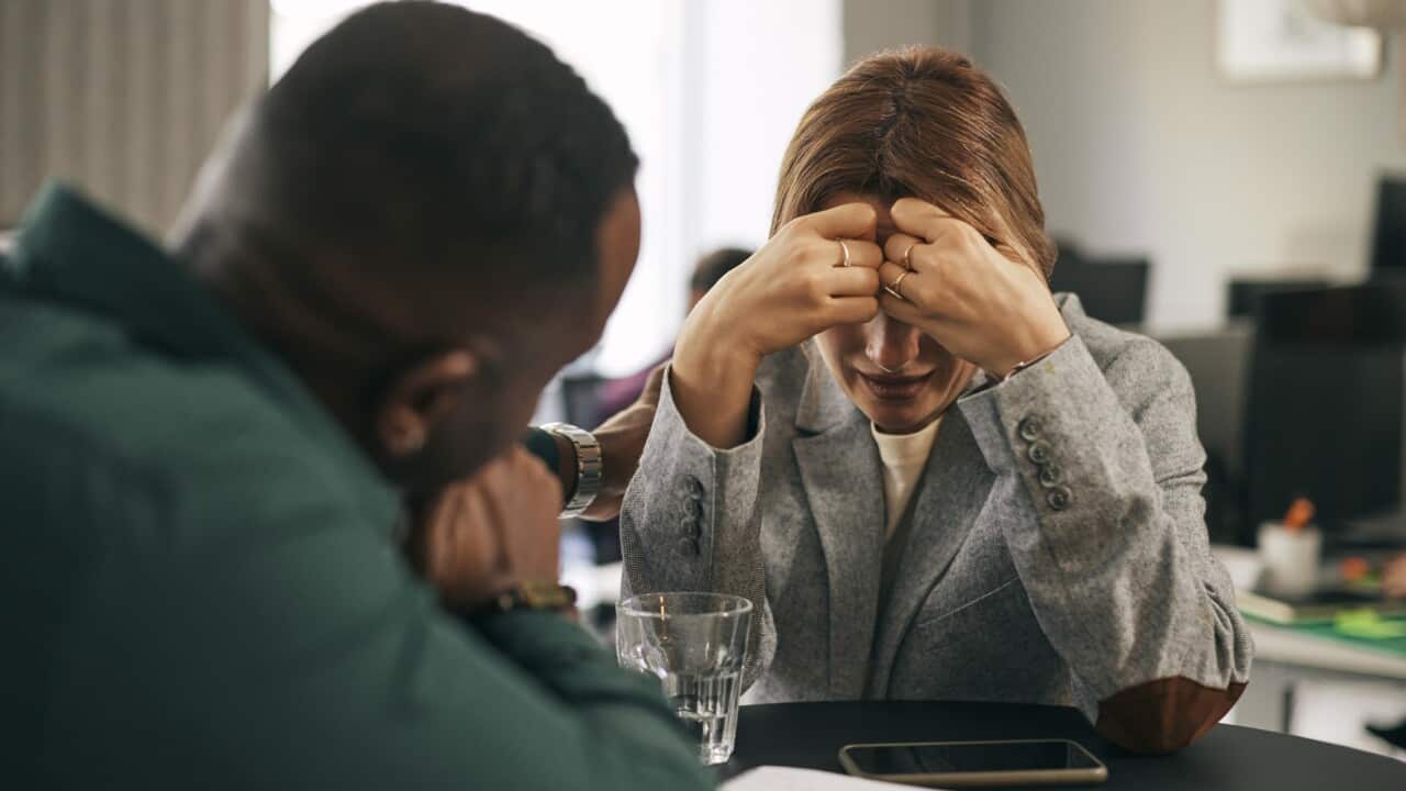 Male business professional consoling crying female colleague in office