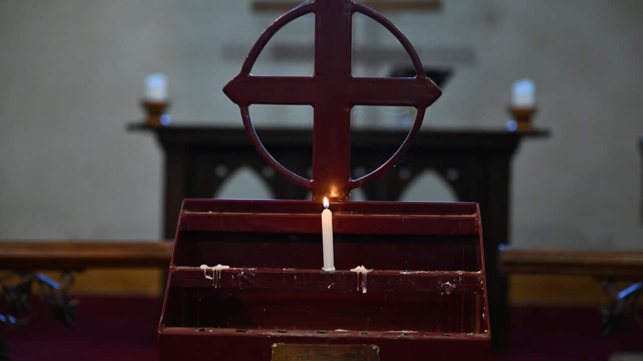 A lit candle is seen on an altar inside a church.