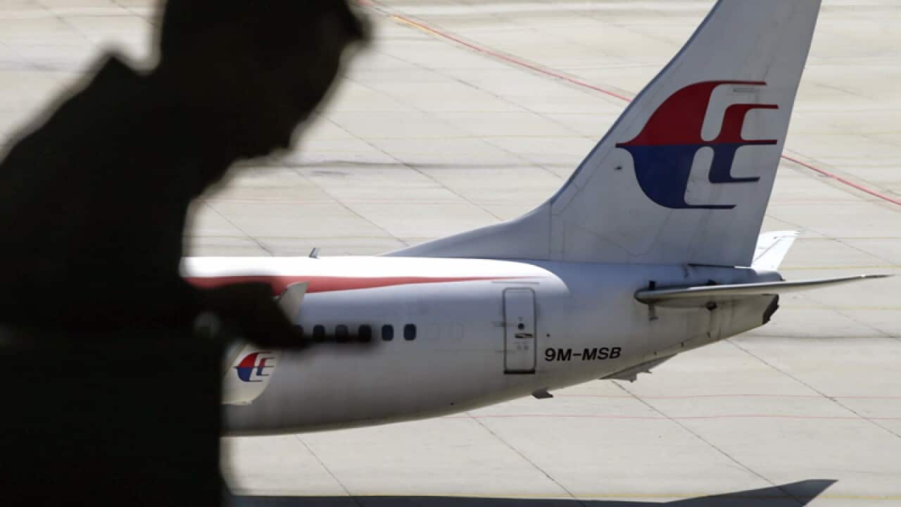 A passenger walking past a Malaysia Airlines aircraft