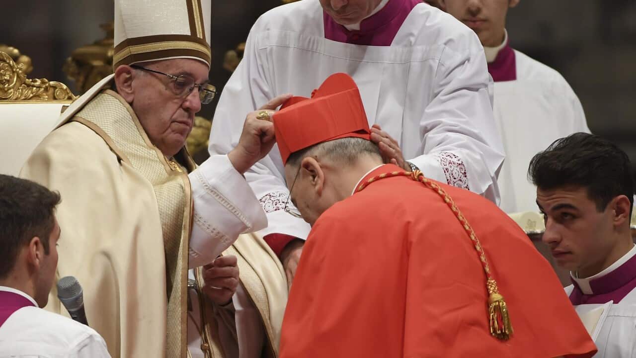 Pope Francis (L) places the red three-cornered biretta hat on the head of new Cardinal Carlos Osoro Sierra.
