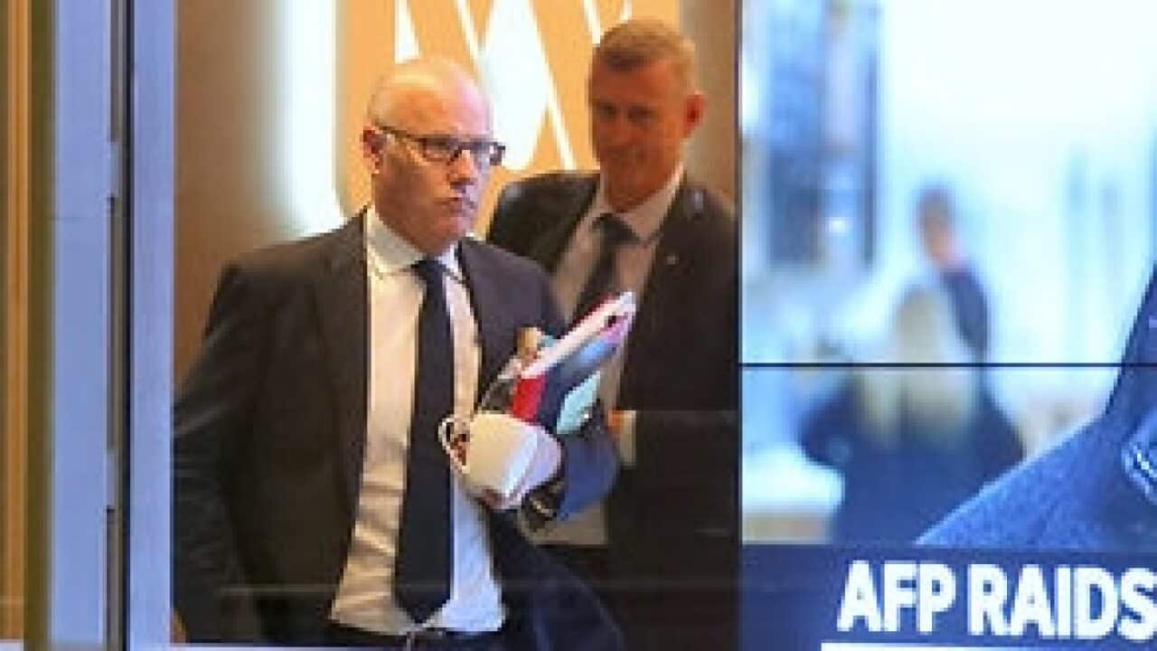 Executive Editor of ABC News John Lyons is followed by an Australian Federal Police officer as they leave the office after the raid.