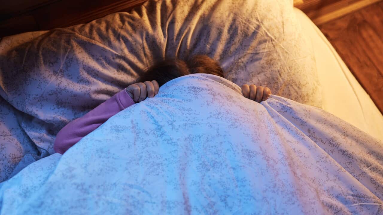 A child hiding blankets over their face.