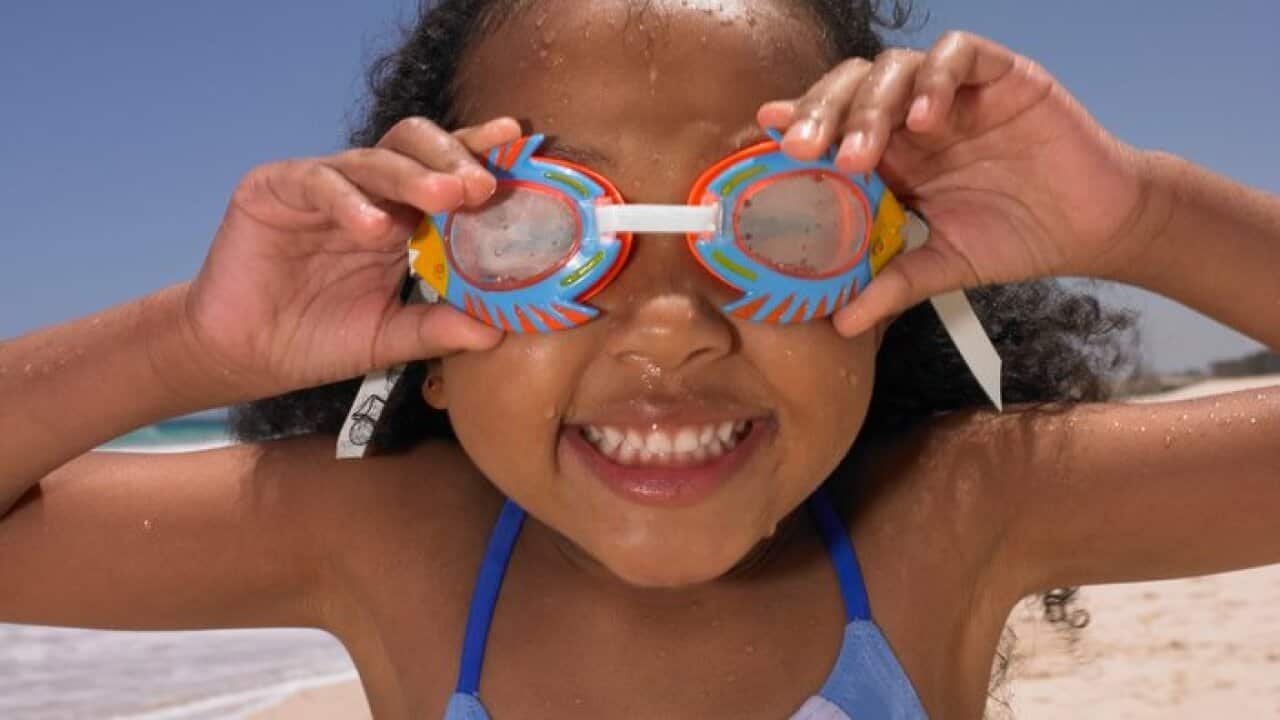 Smiling girl wearing goggles at beach