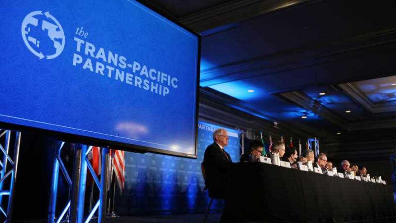 Delegates from 12 countires front the media after signing the Trans-Pacific Partnership free trade pact.