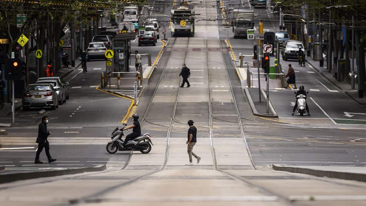 People are seen crossing Collins Street in Melbourne, the world's most locked-down city