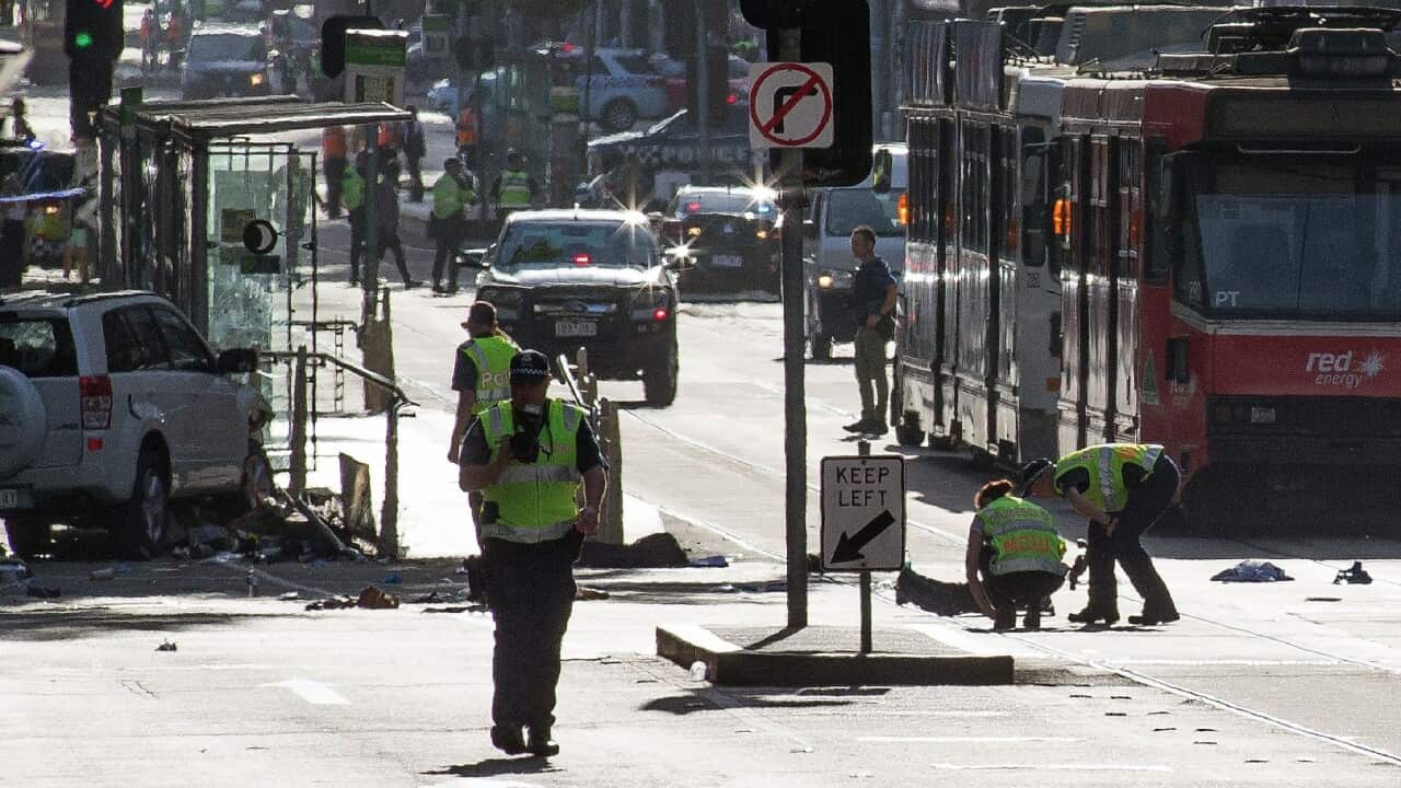 A white SUV (far L) sits in the middle of the road as police and emergency personnel work at the scene of where a car ran over pedestrians in Flinders Street in MelbourneDecember 21, 2017
