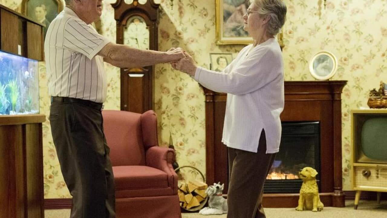 An elderly couple dance together