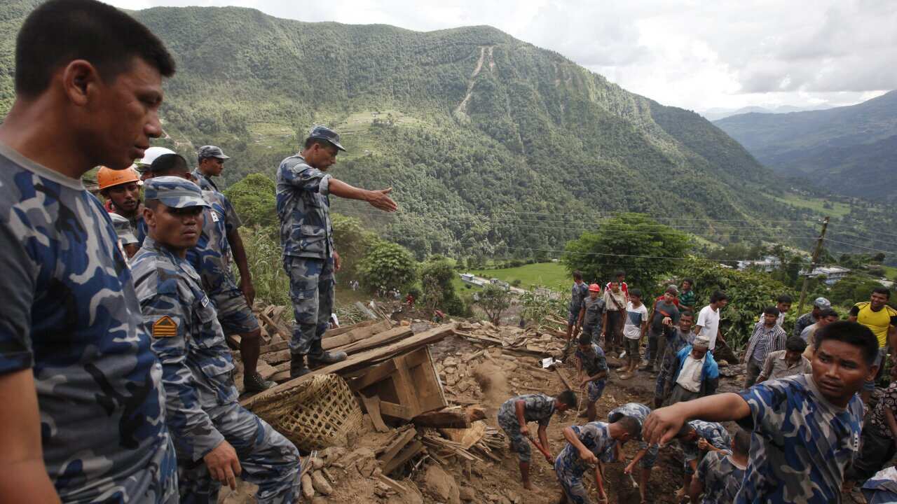 Nepalese policemen search for bodies of victims from the debris after a landslide in Lumle village, about 200 kilometers (125 miles) west of Kathmandu, Nepal, Thursday, July 30, 2015. (AP Photo/Niranjan Shrestha)